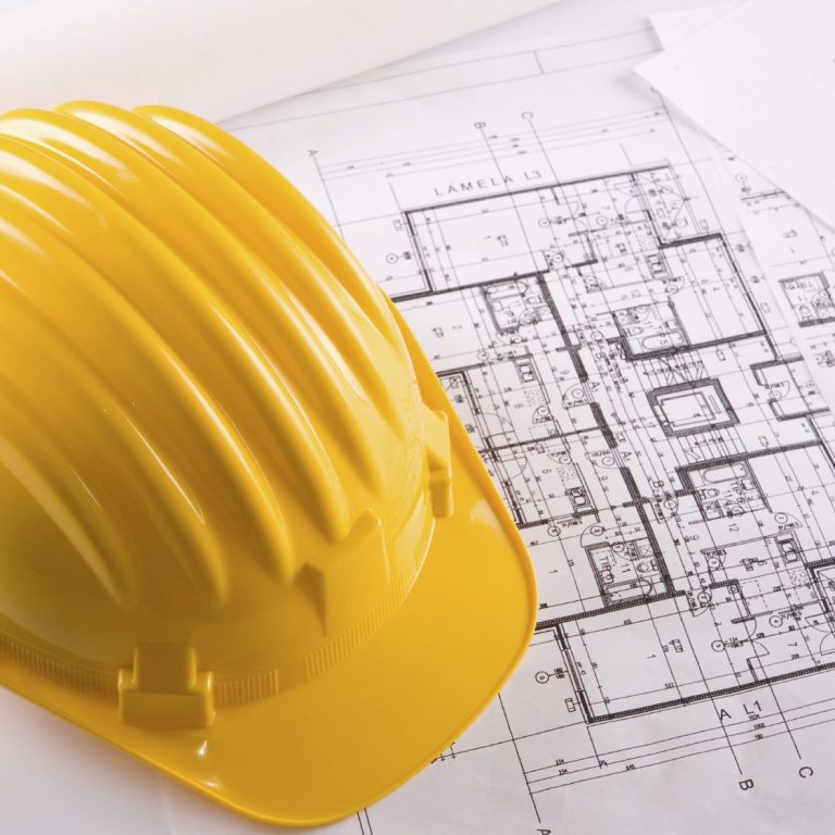 Elmetto di sicurezza giallo su un piano di costruzione architettonico.